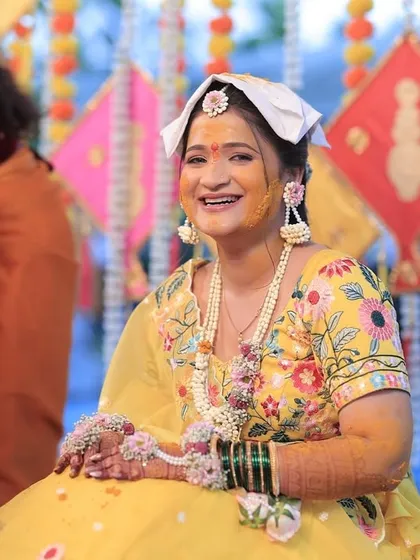 The joy of the Haldi ceremony is perfectly captured here. The bride's smile is as bright as her floral jewellery.