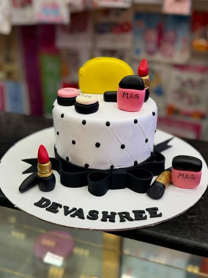 For the makeup lover, this cake is decorated with edible lipsticks, brushes, and compacts. The quilted pattern and black bow add a touch of chic elegance to this stylish and fun design.