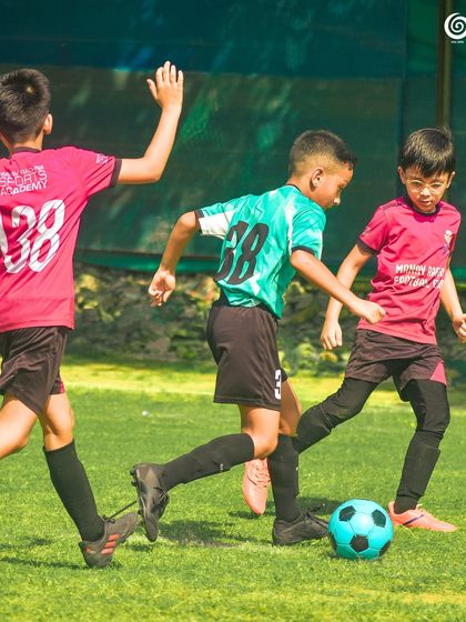 Three young players from Manav Rachna and GSC are involved in a chase for the ball.