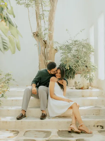 A sweet kiss on the cheek in a bright, airy studio setting. The natural light and clean background keep the focus entirely on the couple's affection.