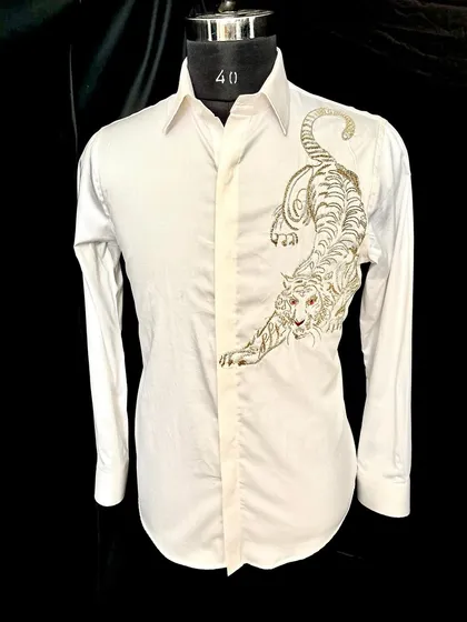 The 'ROAR' collection's white tiger shirt. The powerful, crouching tiger is embroidered in gold and silver thread, creating a design that is both fierce and elegant.
