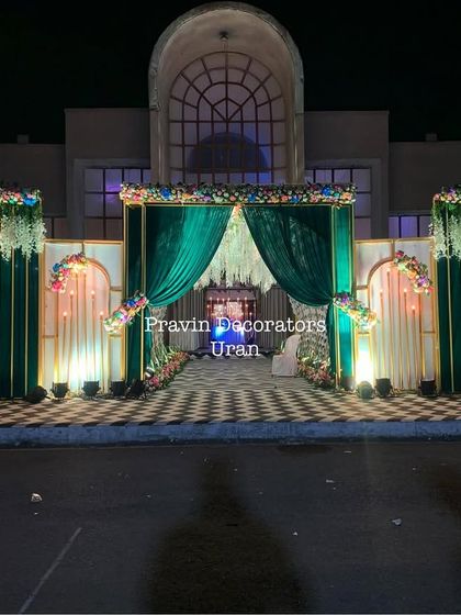 This elegant entrance structure combines rich emerald green drapes with white floral panels and a checkered floor. The design creates a sense of grandeur right at the entrance of the venue.