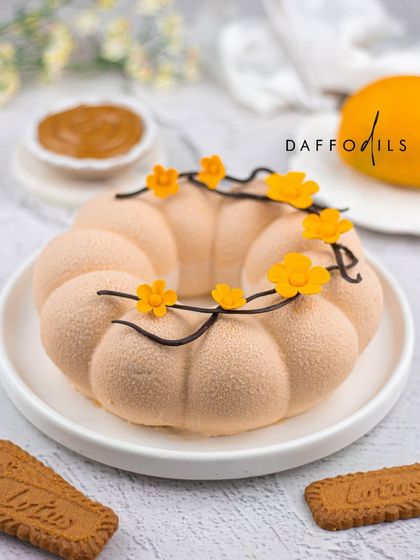 The Mango Biscoff entremet is a match made in heaven. This photo shows the unique flower-like shape, with a velvety texture and edible flower decorations. The spiced caramel notes of Biscoff pair beautifully with the sweet mango.