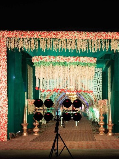 The entrance to a grand Sangeet, designed to build excitement for the night ahead. We used emerald green draping and floral arrangements with hanging jasmine strings to create a fragrant and visually stunning welcome for guests.