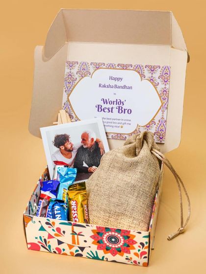 A 'World's Best Bro' Rakhi hamper packed with an assortment of his favorite chocolates and a personalized photo frame, all inside a colorfully printed gift box.