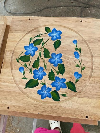 A finished wooden panel featuring delicate blue flowers, ready to be installed as part of the larger ceiling design.
