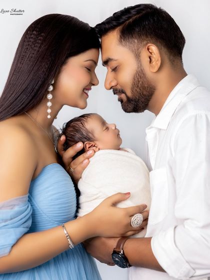 An intimate family portrait, with parents touching foreheads as they gaze lovingly at their newborn. This pose creates a powerful sense of love and unity.