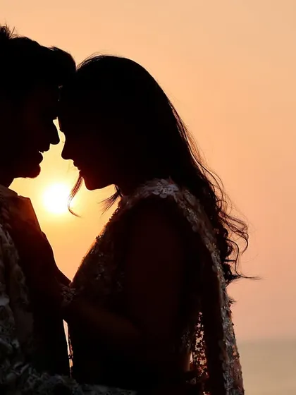 An intimate silhouette of a couple with their foreheads touching as the sun sets behind them. This classic pre-wedding pose emphasizes romance and connection, creating a timeless image.