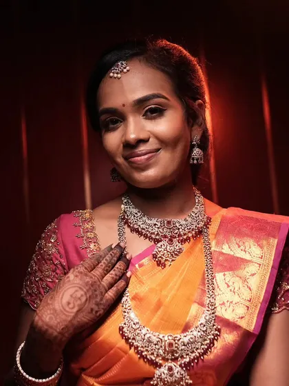 A lovely reception look with a bright orange and pink saree, paired with beautiful silver jewelry.