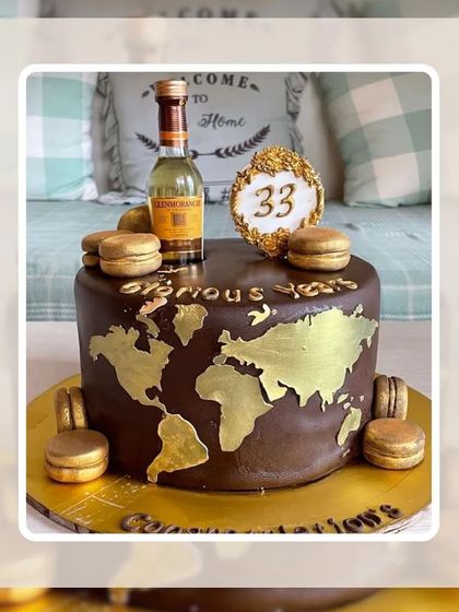 A "33 Glorious Years" cake for a travel lover, featuring a gold world map, macarons, and a miniature liquor bottle.