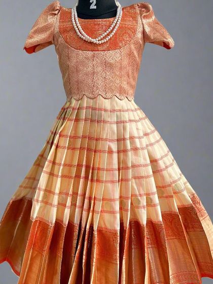 This charming kids' lehenga in peach and orange tones was created from a semi-Kanchi saree. I can create these custom outfits for children, offering a unique and traditional alternative to ready-made dresses.