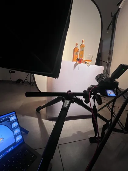 This is the setup for the "liquid gold" Johnnie Walker shot. You can see the large softbox creating the clean white background and the precise placement of the bottles. My laptop shows the tethered image, which is crucial for getting the composition just right.