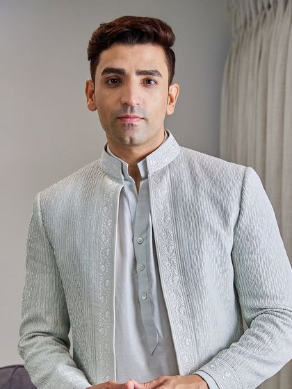 A close-up portrait reveals the subtle sheen of the fabric and the meticulous embroidery detail around the collar and front panels of the jacket.