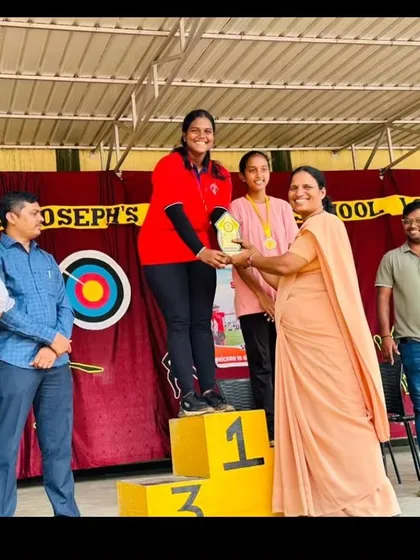 A student receives her first-place award on the podium. These moments of recognition are a powerful motivation for all our archers.
