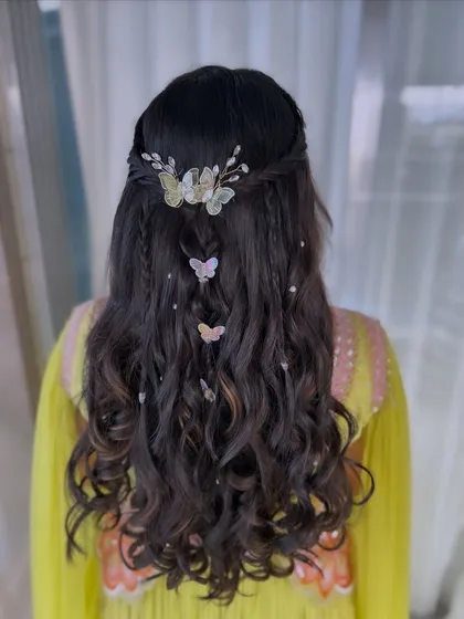 Details make the difference. For this whimsical hairstyle, I added delicate butterfly clips and a floral barrette to a half-updo with soft waves, showing how I love to incorporate unique and personal touches into my work.