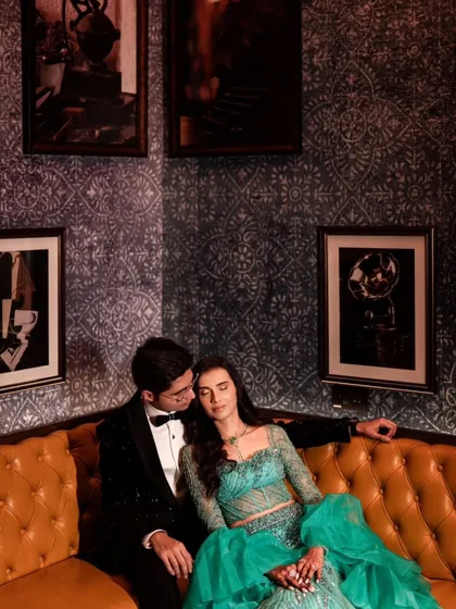 A quiet, intimate moment on a vintage leather sofa. This pose feels natural and relaxed, capturing the couple in a comfortable embrace during their elegant cocktail event.