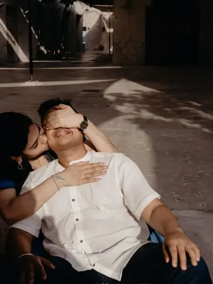 A sweet and playful moment where she covers his eyes and kisses his cheek. The beautiful shadow play in this Dubai alley adds an artistic and intimate touch.