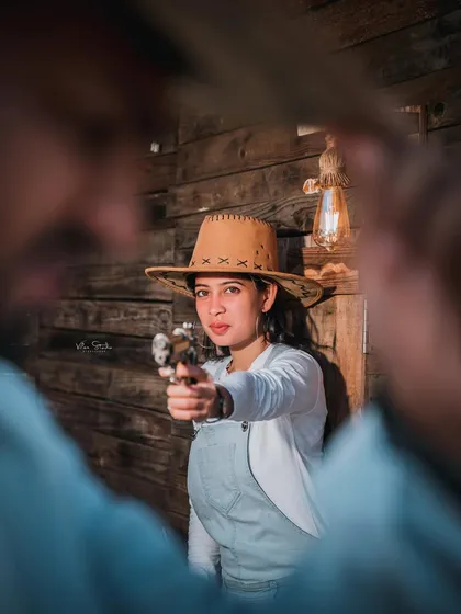 A creative and fun shot from the Western-themed set. The bride-to-be playfully points a toy gun, creating a story-driven and cinematic image.