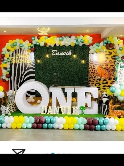A full view of the bold jungle theme party, showing the combination of animal prints, a grass wall, and extensive balloon decorations.