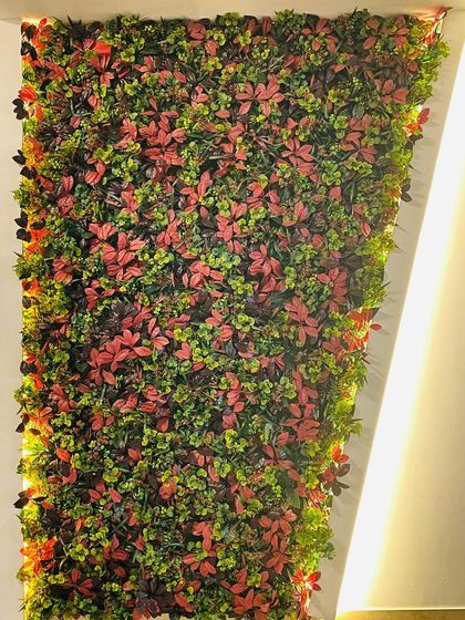 An accent wall featuring our artificial autumn leaves. The mix of red and green foliage creates a warm, inviting atmosphere, perfect for an interior space that needs a touch of color.