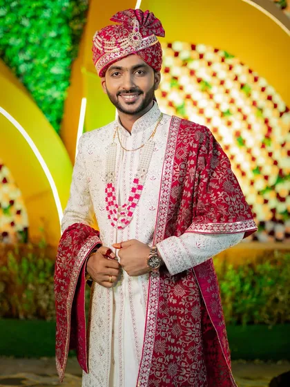 A handsome portrait of the groom, Deepak, in his ivory and red sherwani, ready for his grand wedding.