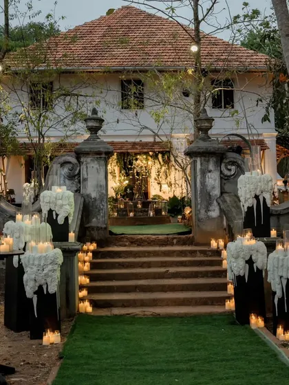 The entrance to this heritage venue is lined with pillars featuring dramatic melted wax-style floral arrangements, creating a gothic-romance feel for the evening celebration.