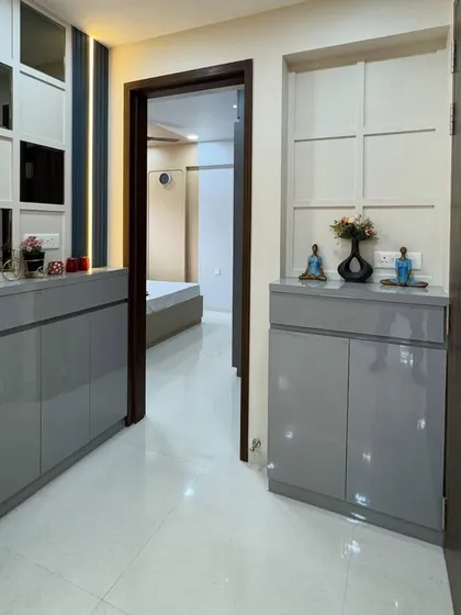 A sleek and functional entryway console in a glossy grey finish. The design includes cabinets for shoe storage and a mirrored panel above to make the hallway feel brighter and more spacious.