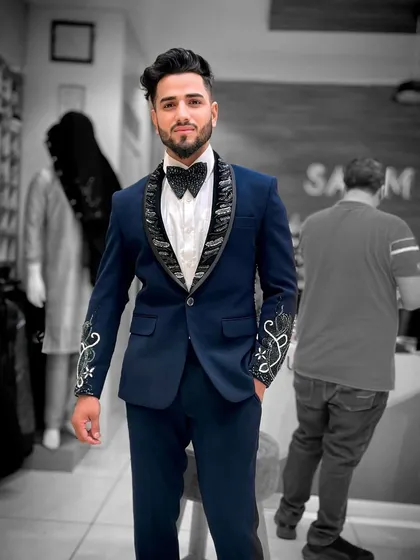 A client in a navy blue tuxedo with embellished lapels and cuffs. The selective placement of the embroidery adds a touch of luxury without being overpowering.