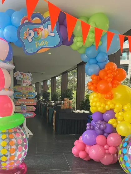 Another view of the lively pool party entrance, with a colorful balloon arch and stacked inflatable beach balls.