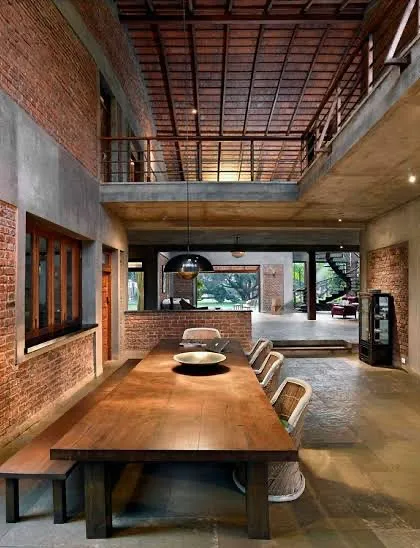 The dining area at The Mango House in Alibag is the heart of the home. Here, exposed brick walls, a double-height ceiling with terracotta tiles, and a large wooden table create a space that is both grand and grounded, perfect for conversations that last for hours.