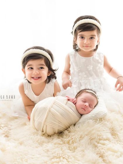 A fairytale scene with two smiling twin sisters and their brand new baby sister. This light and airy portrait is full of innocence and joy.