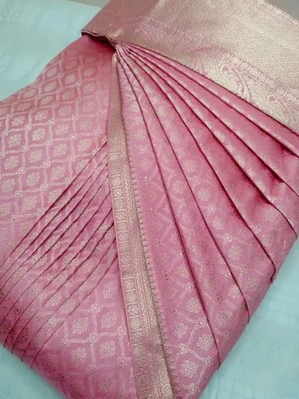 A soft pink silk saree, pleated and ready to be worn.