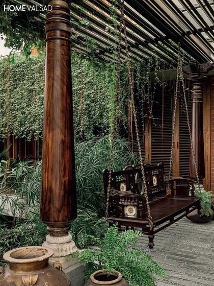 This image, featured in Elle Decor, highlights the traditional swing and reclaimed wooden pillars. The surrounding landscape, with its dense foliage, was designed to create a private, enclosed feeling for this outdoor seating area.