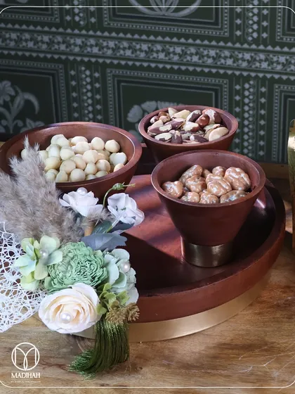 A stylish wooden serving tray with three matching bowls, perfect for serving an assortment of dry fruits or nuts. The warm wood is accented with a brass base, blending rustic charm with modern elegance.