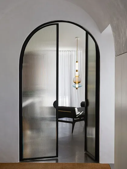 Viewed through an arched doorway, a Luna Kaleido pendant acts as an alluring focal point, drawing you into the next room. This shows how I use lighting to guide movement through a space.