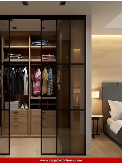 This wardrobe uses black-framed glass sliding doors to create a modern, industrial-inspired look that separates the closet from the bedroom while allowing light to pass through.
