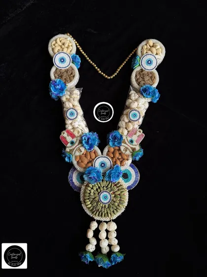 This evil eye dry fruit garland with blue floral accents is designed to bring good luck and festive cheer.
