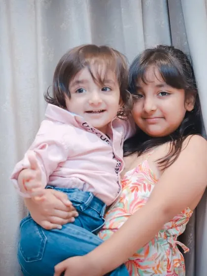 An older sister holds her little brother, both smiling sweetly. Capturing the protective and loving bond between siblings is always a joy.