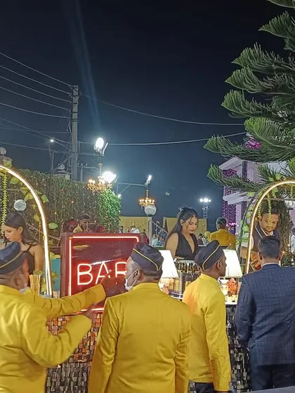 A wide angle view of an outdoor bar setup, with our team serving guests in coordinated yellow uniforms that match the event's color scheme.