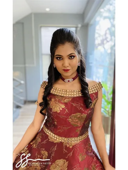 A full sangeet or reception look for a model shoot, featuring a dramatic eye, bold red lip, and a sculpted hairstyle. The makeup is designed to complement the ornate, off-the-shoulder gown.