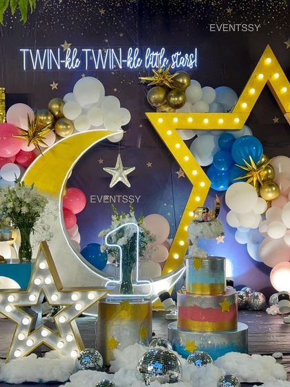 Another angle of the celestial-themed stage, showing the marquee number "1" and a multi-tiered cake. The floor is covered in soft batting to look like clouds, with silver disco balls for extra sparkle.