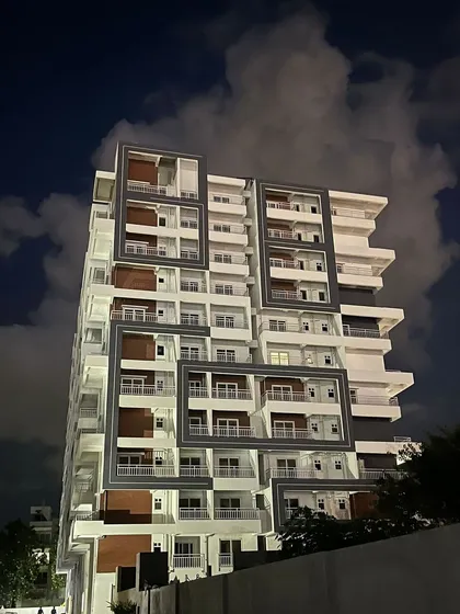 This is the view of a luxury apartment building I designed, seen here at night. The architectural design uses bold, geometric frames to create visual interest and highlight the private balconies, giving the structure a strong, modern identity.