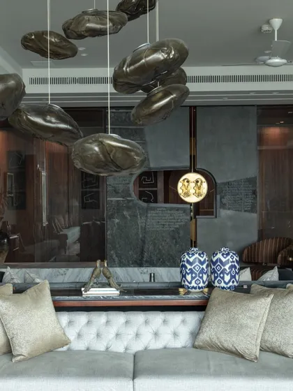 A detail of the living room featuring a massive stone water feature symbolizing blessings. The space is a curated collection of art and bespoke furniture, including antique silver birds from Mumbai's Chor Bazaar.
