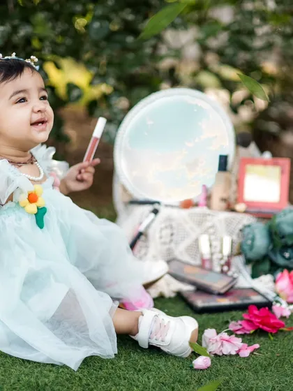 Every little girl loves to play with her mama's makeup. We created this adorable outdoor setup with a mirror and makeup props for a unique first birthday shoot.