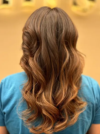 A stunning balayage effect, with a seamless transition from a darker root to lighter, caramel-toned ends, styled in beautiful waves.