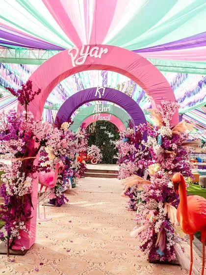 Step into a world of pure joy with an entrance that sets a vibrant tone. We design immersive experiences like this colorful arched walkway, using fabric draping and floral arrangements to build excitement from the very first moment.