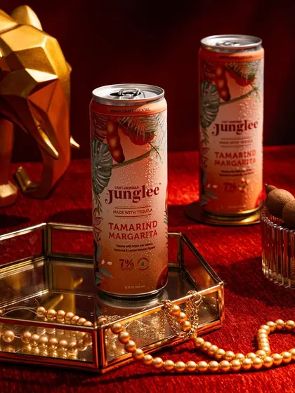 A close-up shot focusing on the Tamarind Margarita can, styled with elegant props like a mirrored tray and pearls to reinforce a premium brand image.