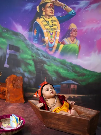 This baby boy relaxes in his boat under the watchful eye of Ekvira Aai. The backdrop and props are designed to tell the story of the Koli community.