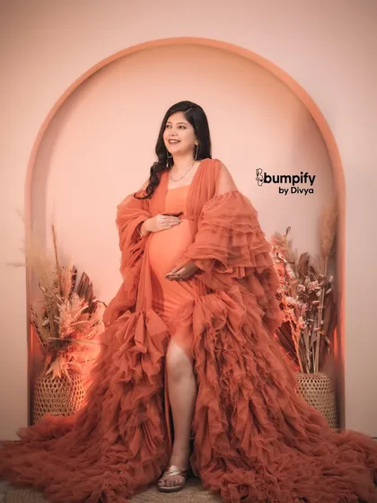 A confident and radiant solo pose. The mom-to-be glows in the orange gown, a perfect celebration of her strength and beauty during pregnancy.