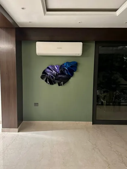 The wider view shows how the sculpture's minimal presence complements the room's dark wood and olive green walls.